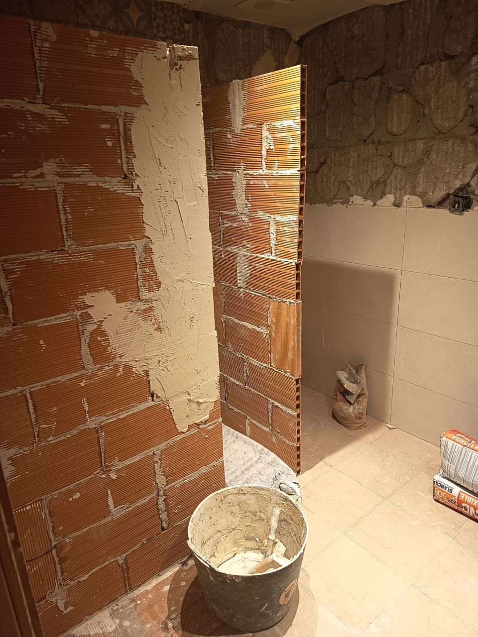 Inicio de la obra: tabiques de ladrillo de la ducha recién levantados y paredes picadas hasta el ladrillo