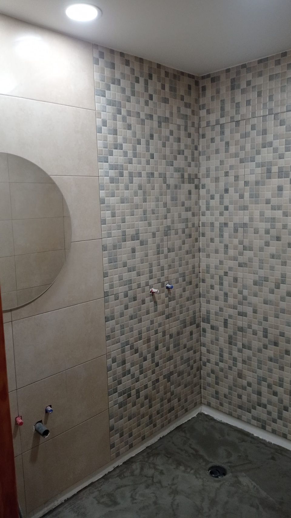 El mismo baño durante la obra: mosaico colocado, suelo aún en cemento y tomas de agua pendientes
