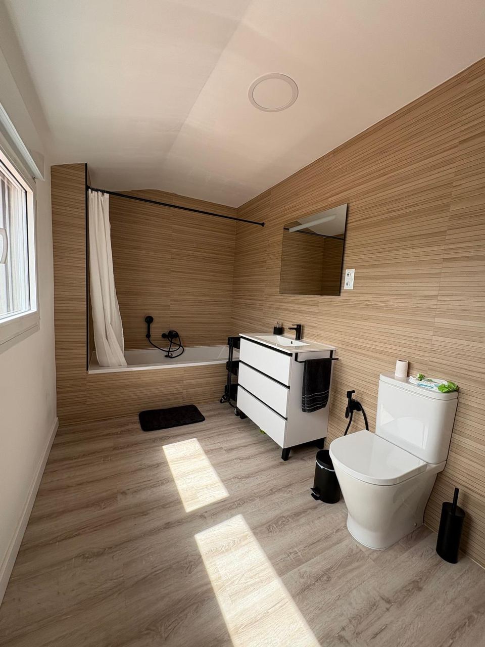 Baño con bañera y revestimiento cerámico efecto madera