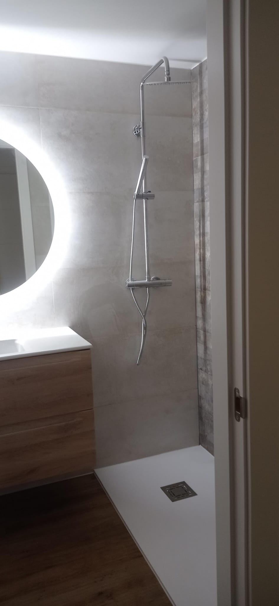 Baño con espejo redondo con luz LED y ducha de obra
