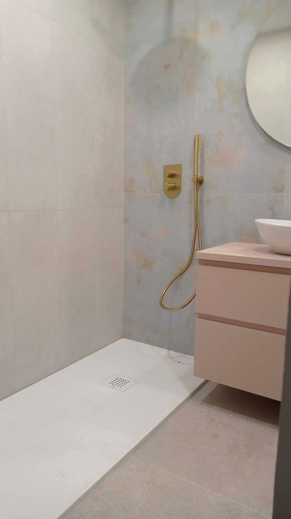 El mismo baño terminado: plato de ducha blanco, grifería dorada y mueble de lavabo