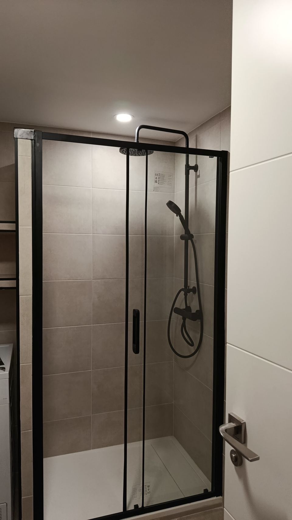 Ducha de obra con mampara de perfil negro y columna de ducha negra