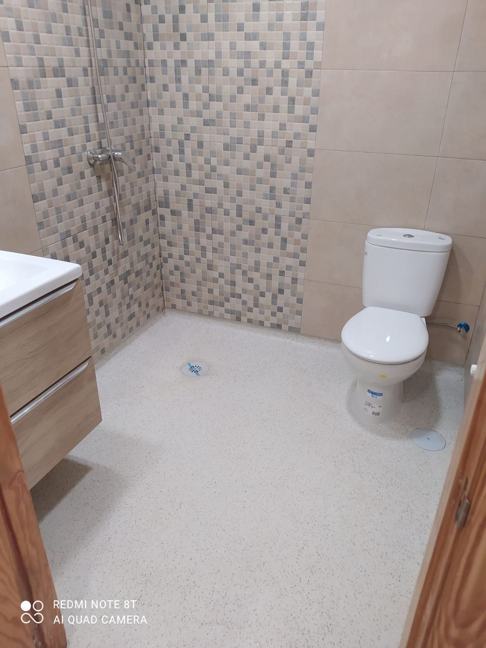 Baño con mosaico en la zona de ducha y mueble de madera