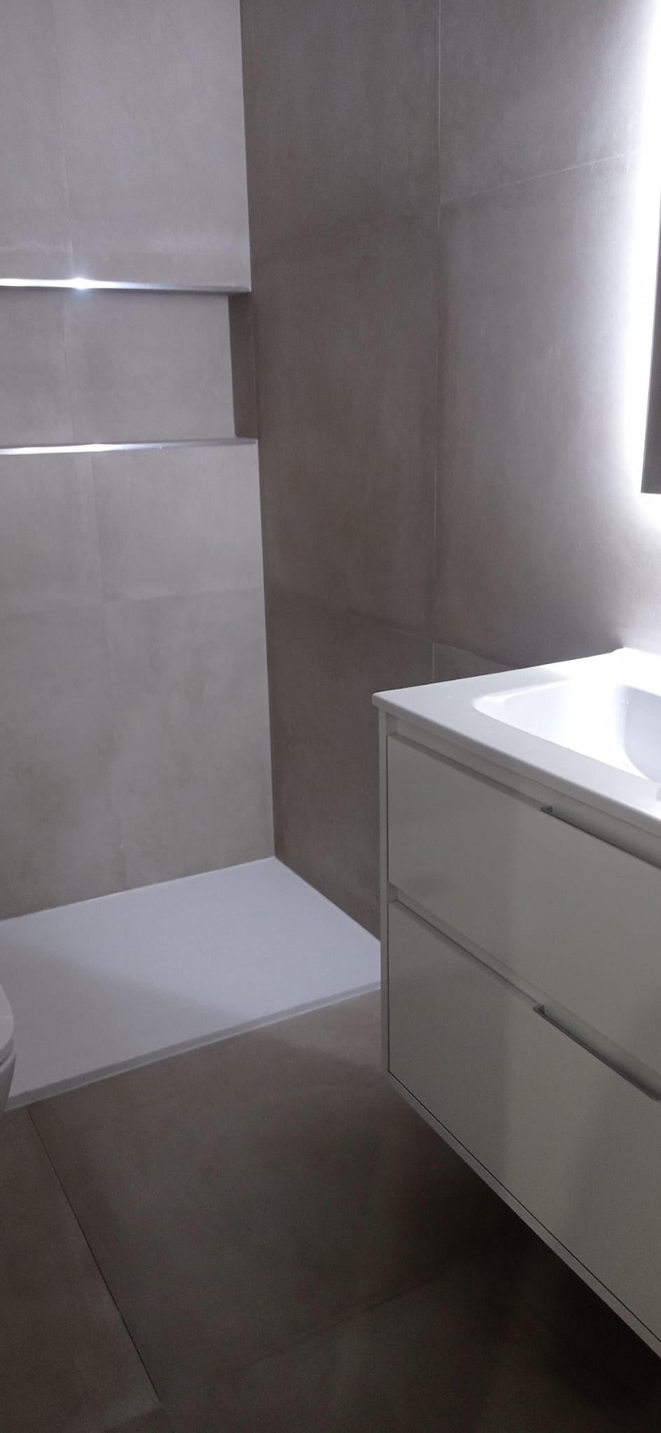 Baño con mueble suspendido blanco y azulejo claro