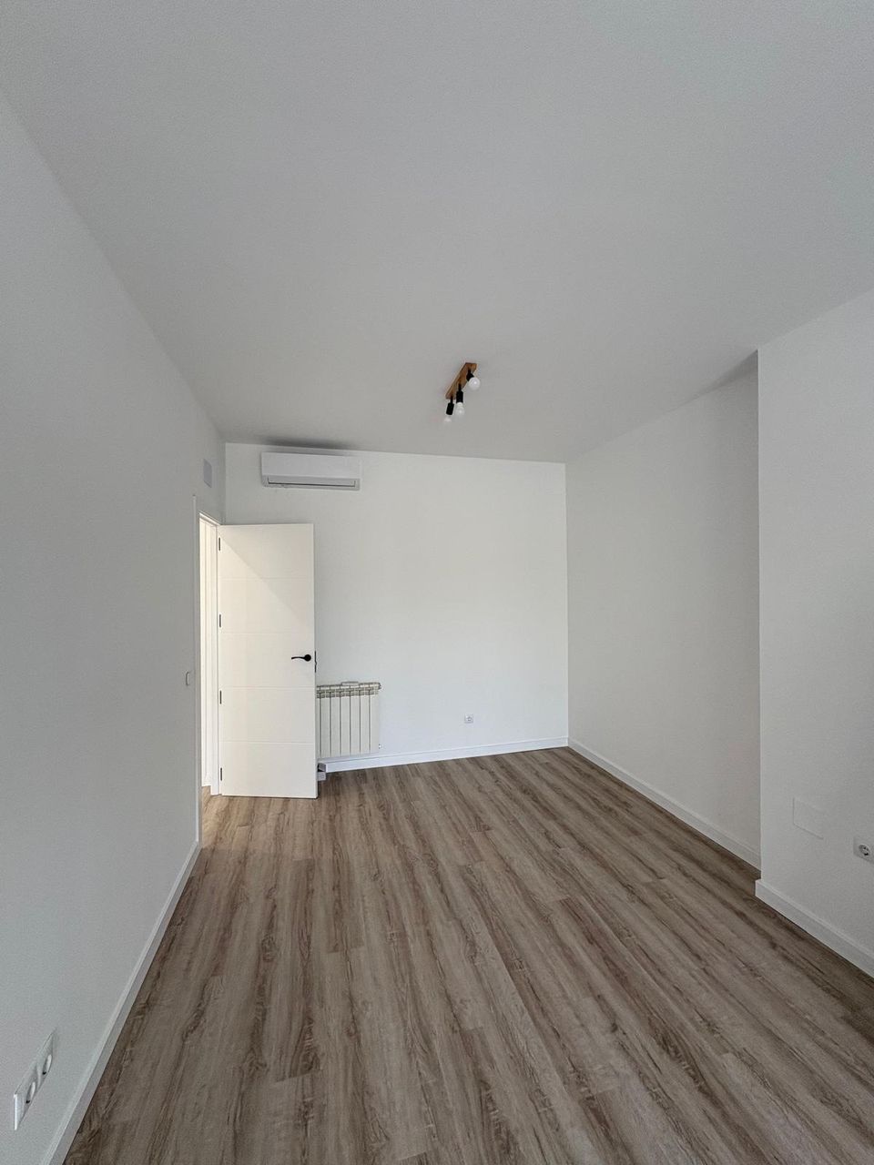 Segunda habitación terminada en la buhardilla, con suelo de madera, radiador, aire acondicionado y puerta lacada en blanco