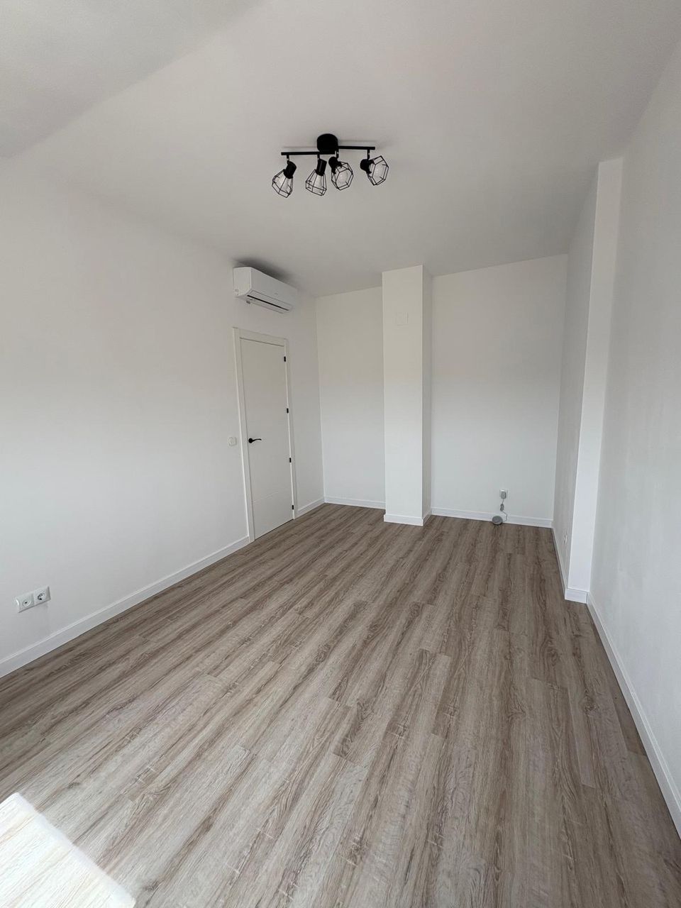 Dormitorio terminado en la buhardilla: paredes blancas de pladur, techo inclinado, suelo de madera, aire acondicionado y lámpara de focos