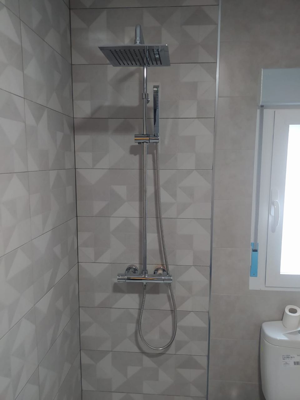 Ducha con azulejo geométrico en gris y grifería cromada