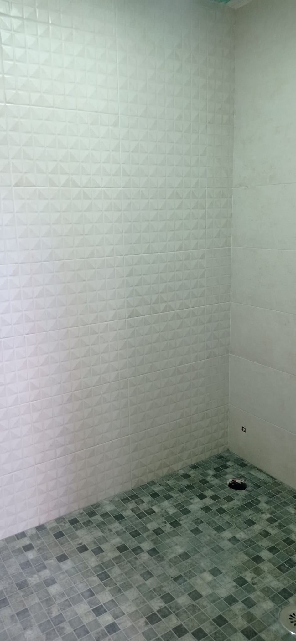 Ducha con azulejo blanco en relieve y mosaico verde en el suelo