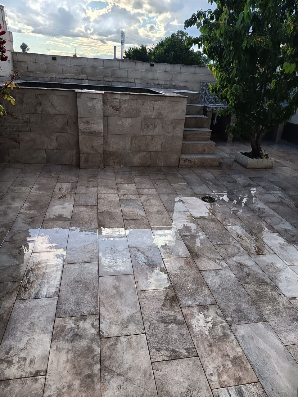 Piscina terminada con su escalera exterior y el patio solado a juego, tras la lluvia
