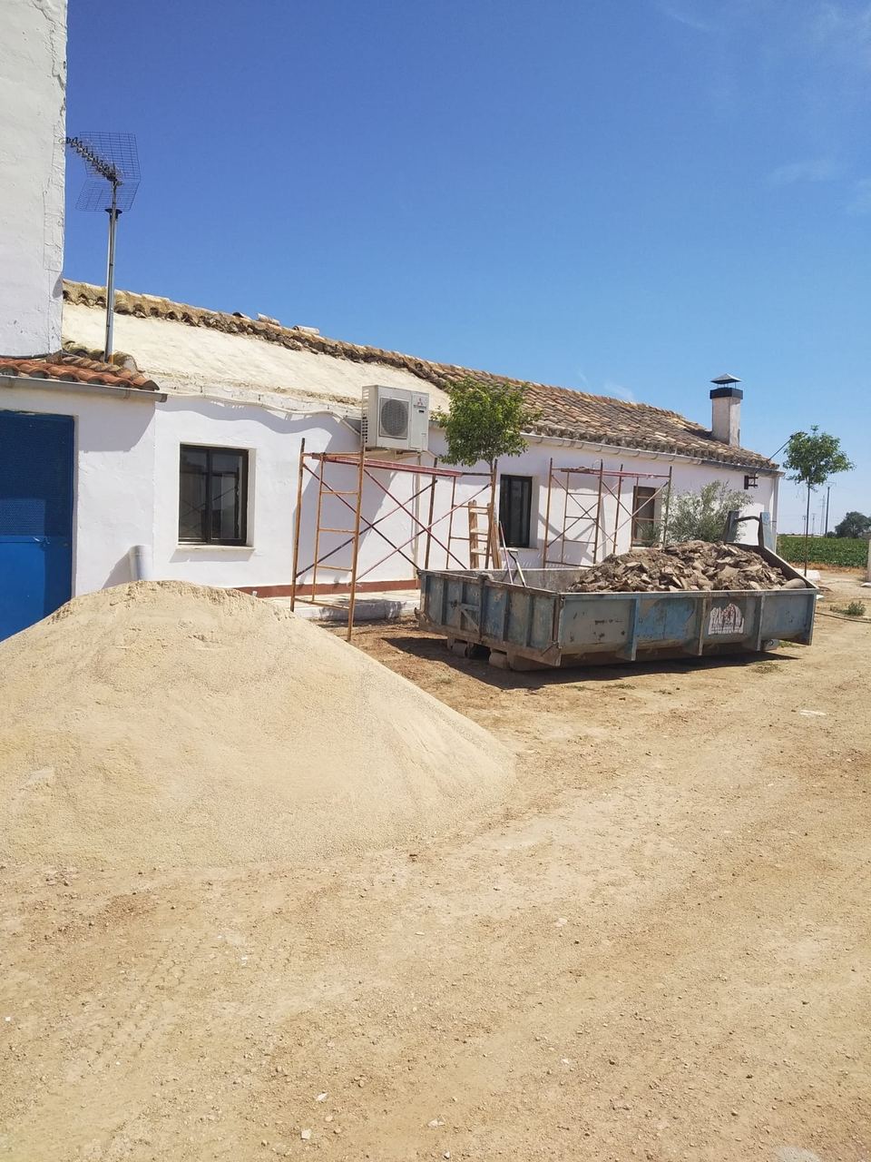 Casa de campo durante la reforma exterior, con contenedor de escombros
