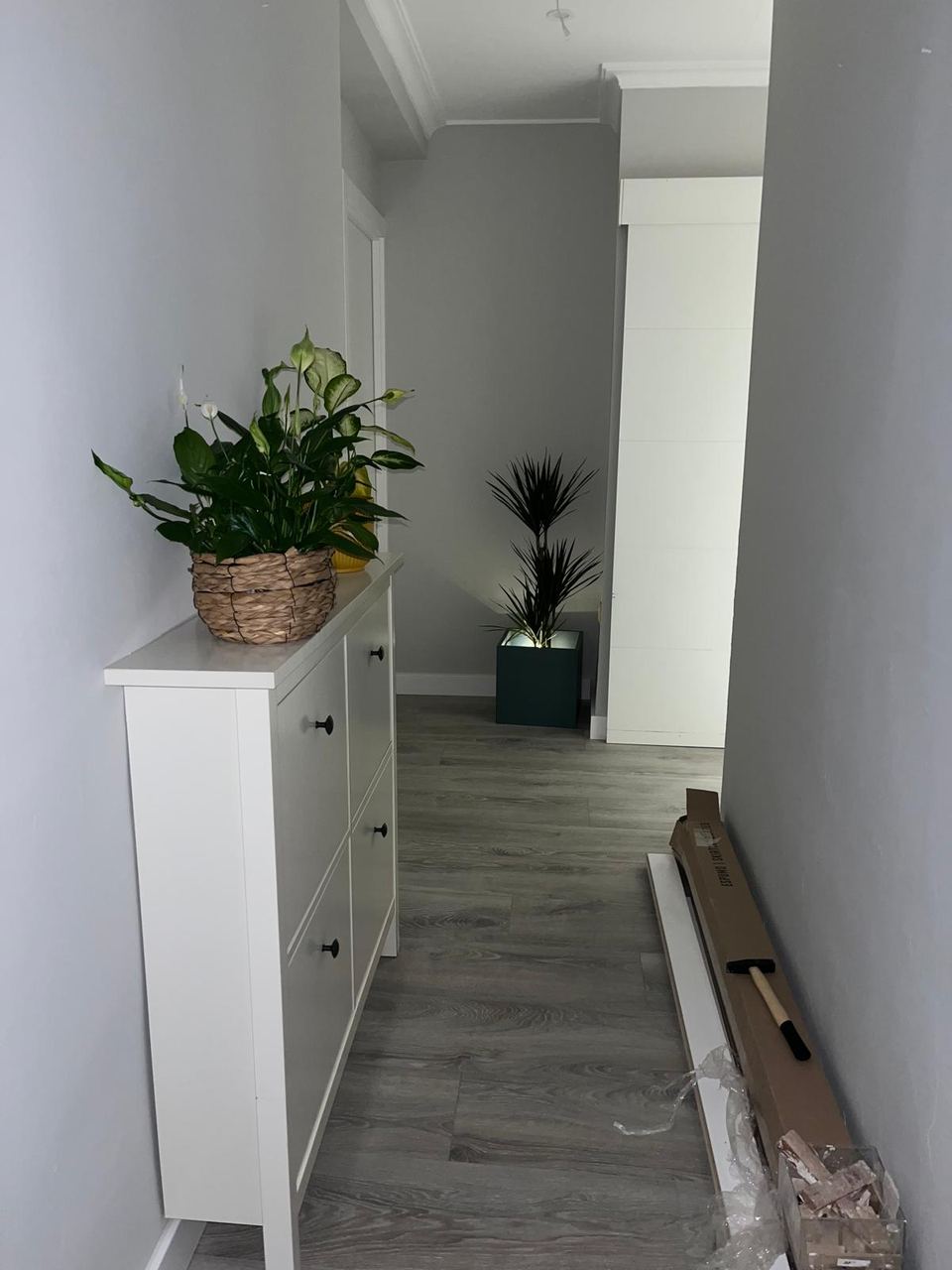 Pasillo de una vivienda tras una reforma integral, con tarima y puertas lacadas en blanco