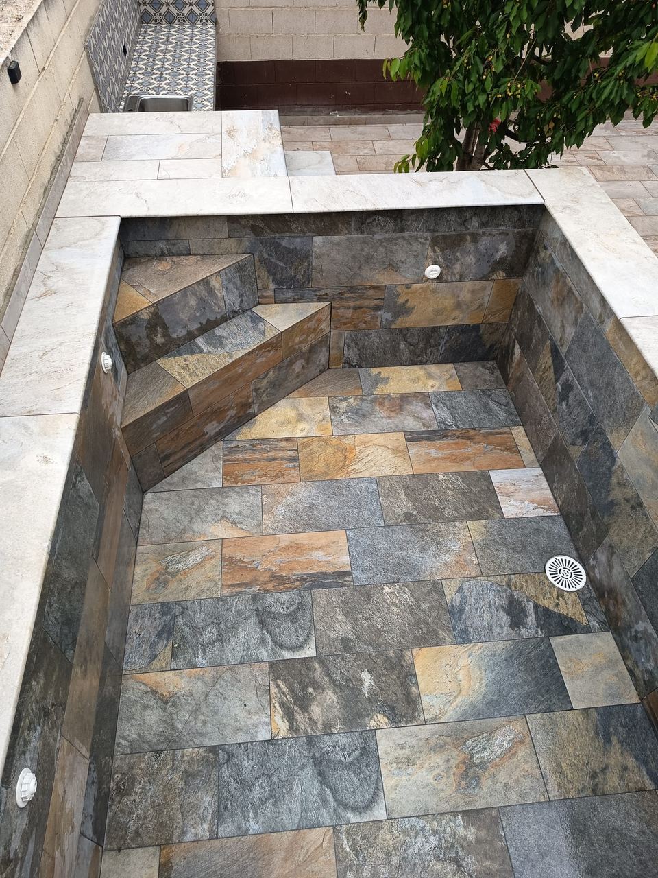 Piscina de obra terminada, revestida con gres porcelánico efecto piedra