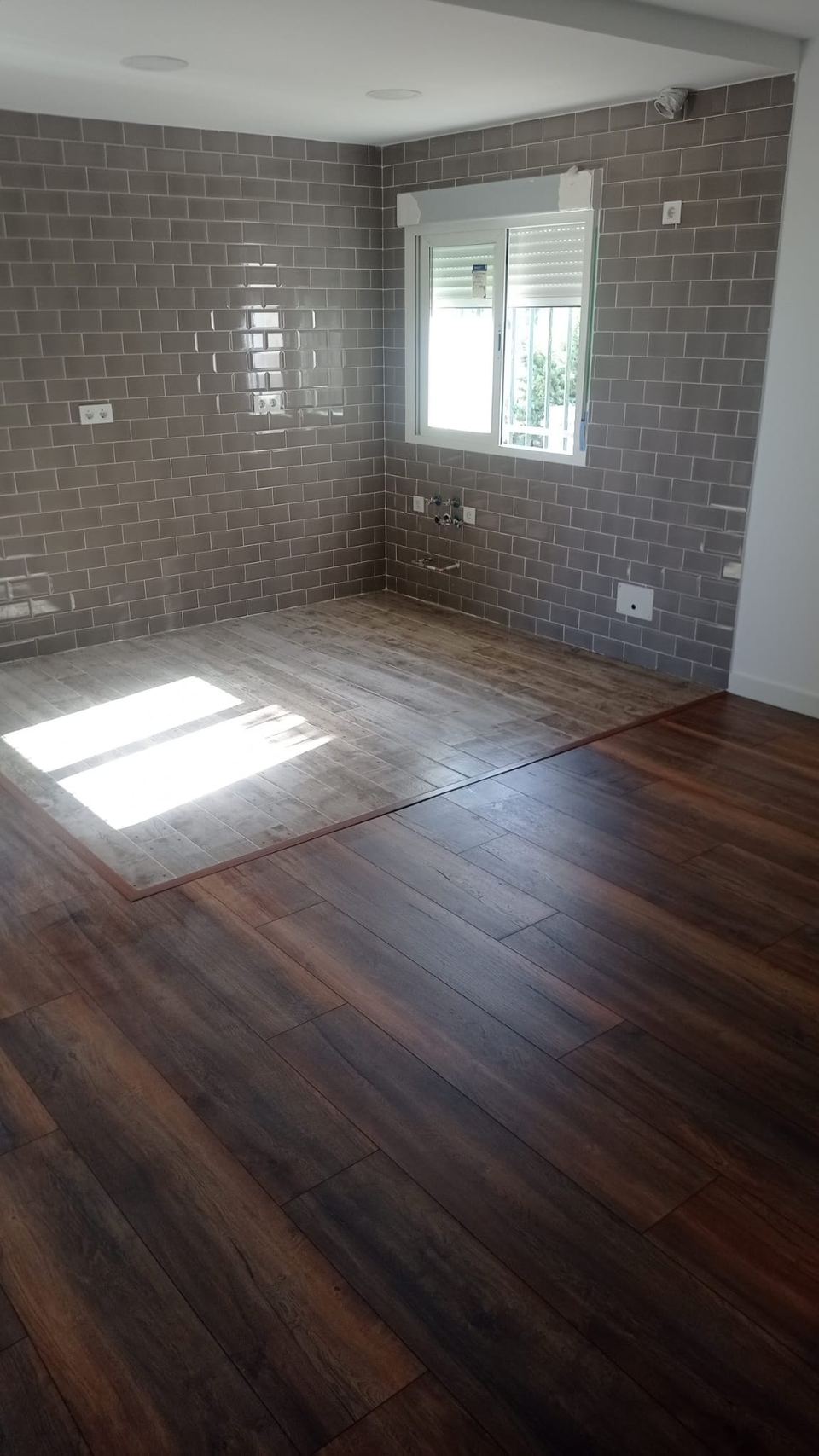 Salón con tarima de madera combinada con porcelánico gris