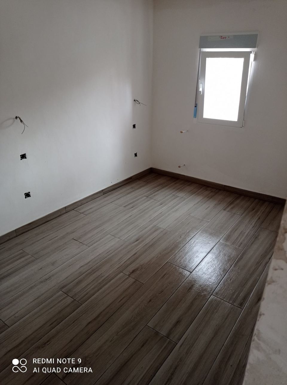 Salón reformado con suelo efecto madera y ventana nueva