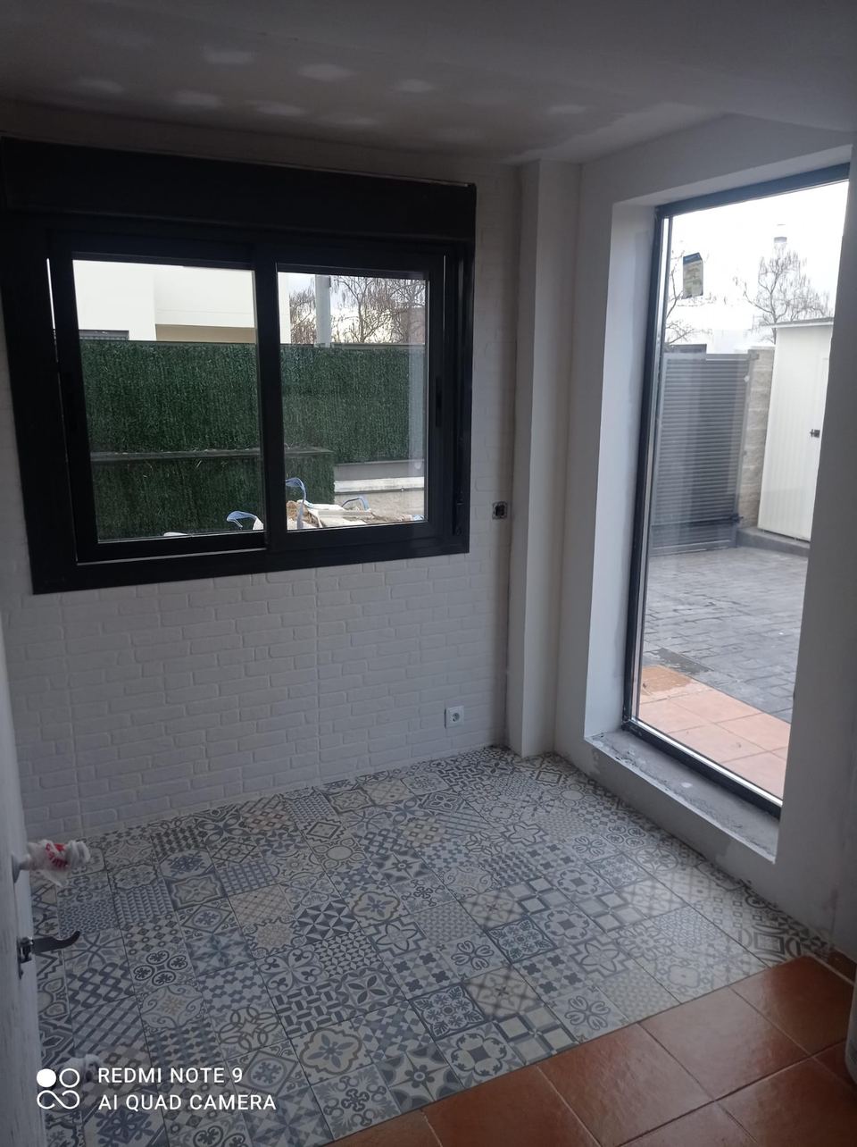 Salón con ventanal de aluminio negro y suelo porcelánico