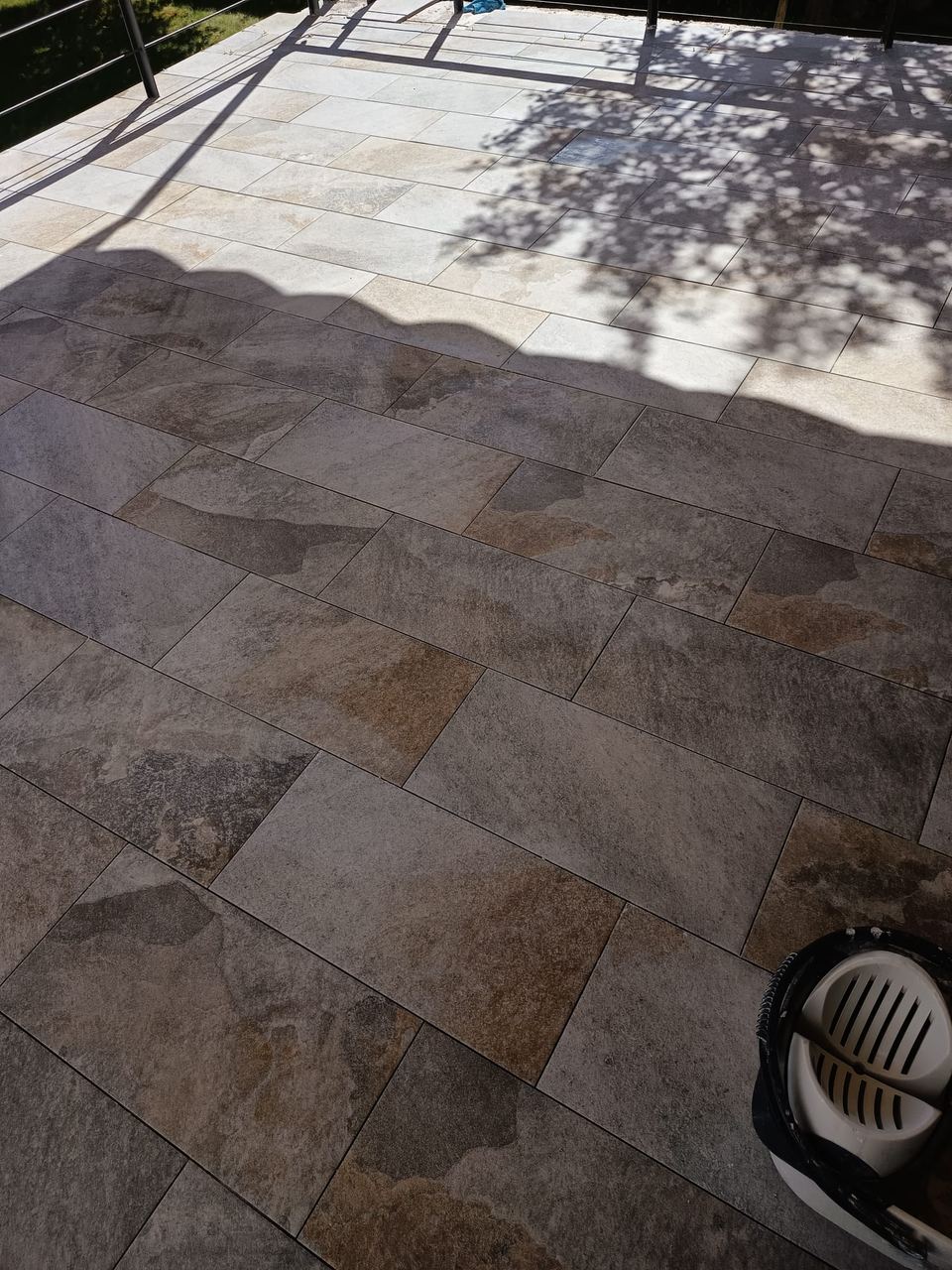 Terraza con solado porcelánico efecto piedra bajo un árbol